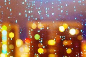 Rain drops and colorful lights of city houses in blur photo