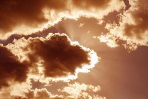 Dramatic view on a orange sky with the sun's rays shining through the dark clouds photo