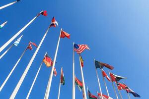 Bottom view of a rows of flags of different countries of the world, flutters in the wind, against a clear blue sky with copy space photo