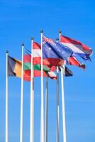 Flags of different countries, flutters in the wind, a background of clear blue sky photo
