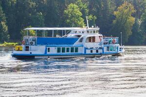 a small ship on the water illuminated by sunlight a background of green trees on the shore photo