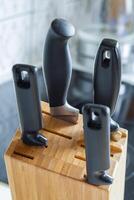 Close up view of a wooden stand with four stab knives on a background of kitchen in bokeh photo