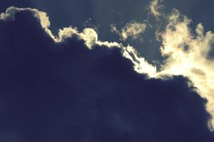 Dramatic view of a dark storm clouds illuminated along the edge by golden sunlight photo