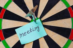 Dart hit the centre of target and attaches sticker with inscriptions meeting photo