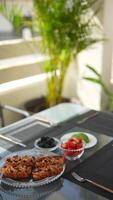 Enjoy breakfast outdoors with pastries and fruits at a patio table in a peaceful and lively setting video
