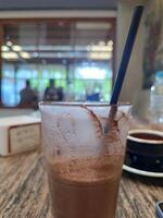 vaso de con hielo chocolate té servido en de madera mesa en cafetería. foto