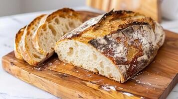 Rustic sourdough bread loaf with a crispy crust, sliced and displayed on a cutting board. photo