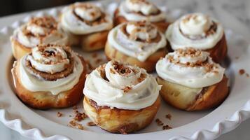 Homemade cinnamon rolls with cream cheese frosting, arranged on a white platter. photo