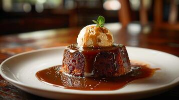 Sticky toffee pudding topped with warm toffee sauce and a scoop of vanilla ice cream. photo