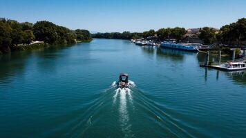 Romantic image with boat in the Rhone river passing through the city of Avignon. boat with water trail photographed by a drone. Provence tourist and historical place. photo