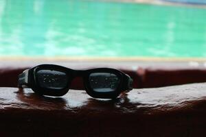 black swimming goggles with a swimming pool in the background photo