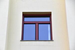 A red window on a yellow wall. A beautiful window in a classic building. photo