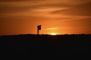 A beautiful sunset and a birdhouse on the horizon background. Rural landscape. photo