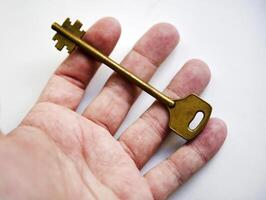 A copper key in his hand on a white background. The key to the front door. photo