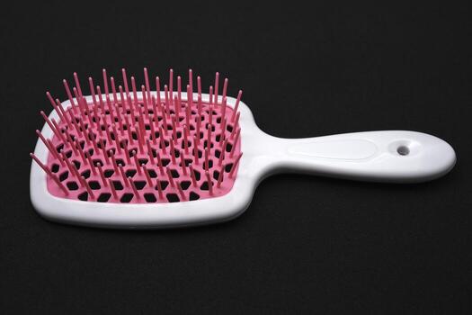 rojo y rosado masaje peine en un negro antecedentes. un pelo y cuerpo cepillar. foto