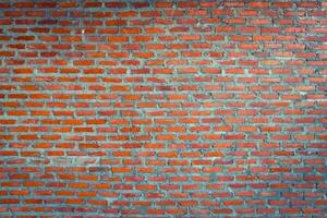 Red brick wall background with uneven texture and varying brick sizes. photo