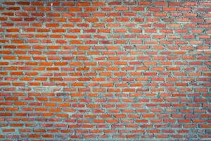 Red brick wall background with uneven texture and varying brick sizes. photo