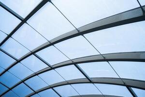 A large, curved glass structure with a blue tint. The glass is arranged in a way that creates a sense of depth and movement, giving the impression of a dynamic and ever-changing environment photo
