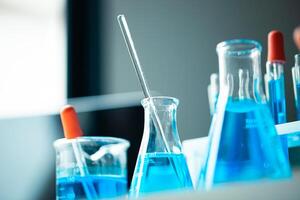 A row of blue beakers with a blue liquid in them. The beakers are arranged in a row and are all the same size photo