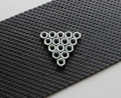 Hex Nuts In A Form Of Play Sign On A Plastic Protection Panel On A White Surface photo