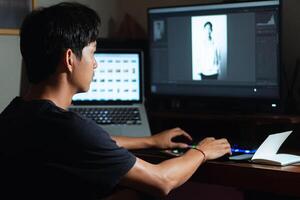 Photo editor working on computer with photo gallery on laptop