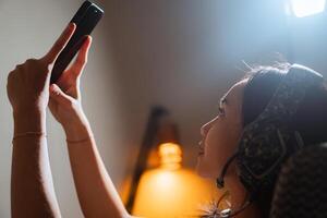 Woman taking a selfish with a smart phone in a dimly lit room photo