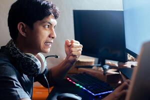 Frustrated gamer clenching fist at computer screen photo