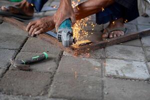Worker using angle grinder to cut metal photo