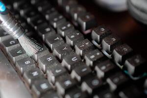 Cleaning a dusty computer keyboard with a brush photo