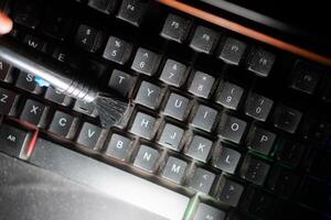 Cleaning a dusty computer keyboard with a brush photo
