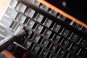 Cleaning a dusty computer keyboard with a brush photo