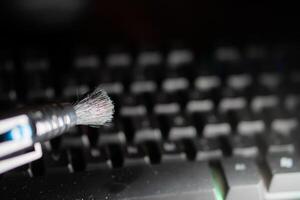 Cleaning a dusty computer keyboard with a brush photo