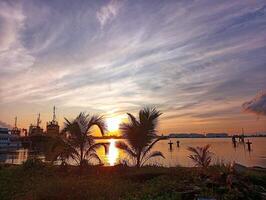 Silhouette of palm trees on the beach with beautiful sunrise view on the sea photo