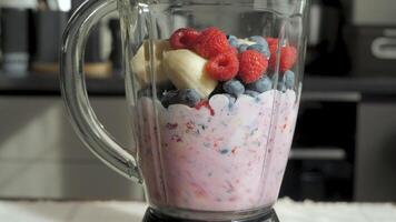 A close-up shot of a blender with banana slices, raspberries, and blueberries inside. The smoothie ingredients are ready to be blended. Healthy organic food. video