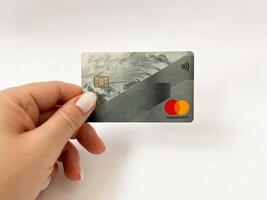 Bialystok, Poland - 08.07.2021 Mastercard bank card in hand on a white isolated background. Non-cash payments with a Mastercard card. Online card payments photo