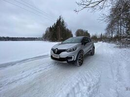 Grodno, Belarus-01.31.2021 Renault Kaptur or Renault Captur SUV on a winter road against the background of a field and forest. Winter driving conditions in Renault on a snowy road photo