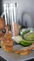 Hands slice bread in a busy kitchen with fresh vegetables, creating artisanal culinary atmosphere video