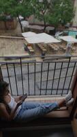 A woman is reading indoors on a rainy day with a view of greenery through a window video