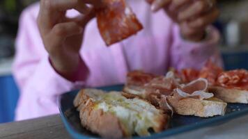 A person enjoying a assortment of sliced cured meats, bread, and snacks in a laidback setting video