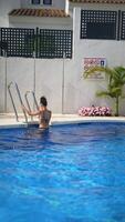 A woman is peacefully relaxing in a pool with flowers and palm trees, enjoying the sunny weather video