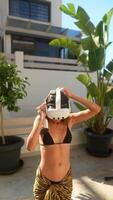 A young girl wearing a VR headset enjoys outdoor fun while dressed in a swimsuit video