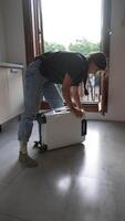 A person is packing a suitcase in a modern home with sunlight through the window video