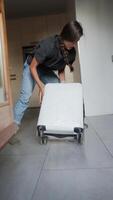 A person is busy packing a white suitcase in a modern home environment with tiles and stylish items video