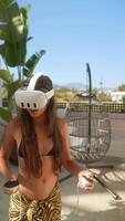Woman in VR headset relaxes on balcony with mountain views, enjoying digital experience video