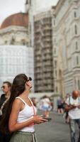 Woman happily exploring city streets in summer, smiling and using a mobile phone video