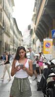 A woman is using her smartphone while exploring a city street with a urban background video