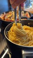In the image, spaghetti is being served from a pot using pasta tongs in a detailed manner video