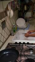 The process of washing dishes in the sink typically involves using soap and water to clean utensils video