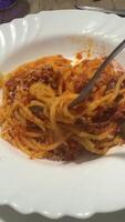 Enjoy a plate of scrumptious Spaghetti Bolognese served with a fork on a white plate video