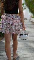A woman wearing a floral skirt is holding a VR headset while standing on a pedestrian bridge video